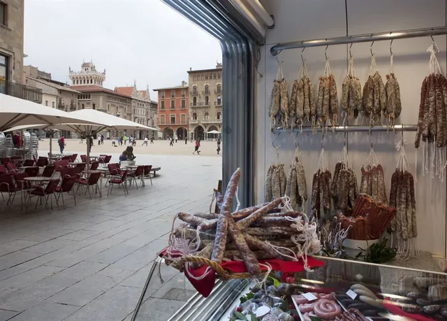 Aparador de Xarcuteria Solà amb fuets i llonganisses penjats, amb la Plaça Major de Vic al fons
